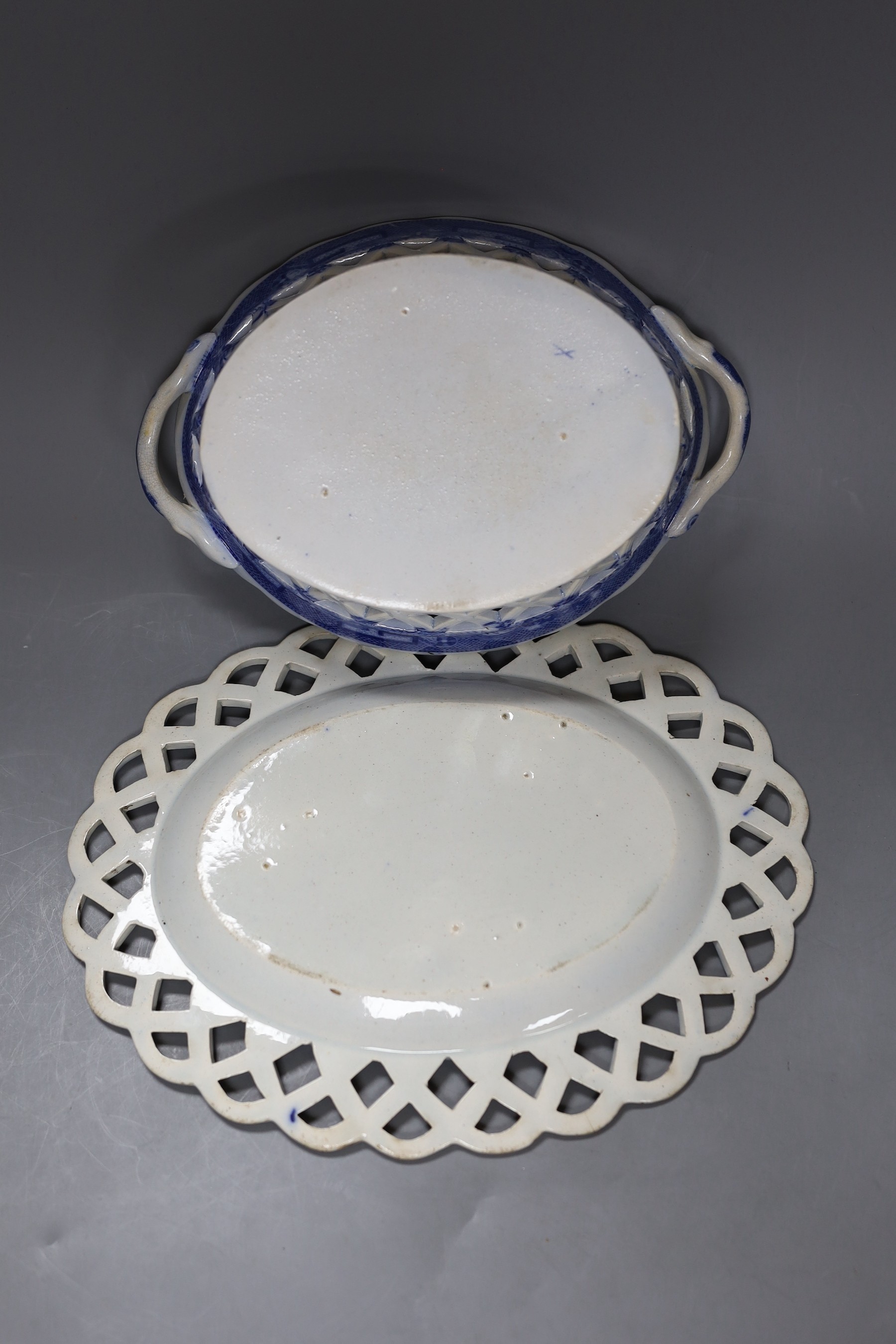 An early 19th century English blue and white pearl ware oval two handled chestnut reticulated basket with transfer printed chinoiserie decoration, together with a similar oval stand